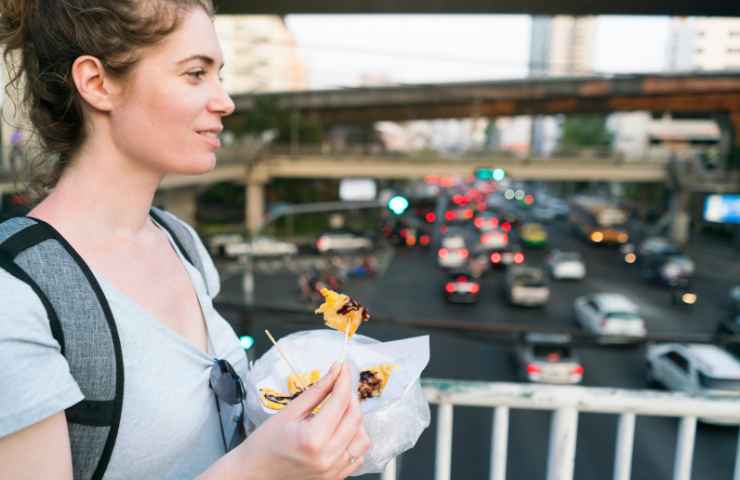 ragazza felice che mangia in strada