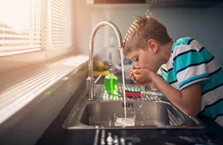 Ragazzini beve acqua di rubinetto